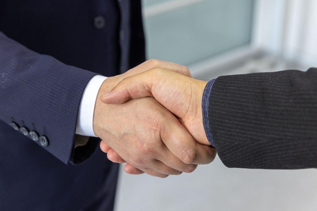 The Art of Drawing Readers In: Your attractive post title goes here Close-up of two business professionals shaking hands, symbolizing partnership and collaboration.